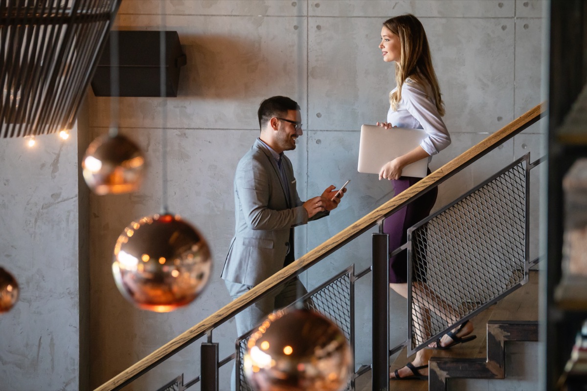 Two colleagues talking on a staircase in a modern office building
